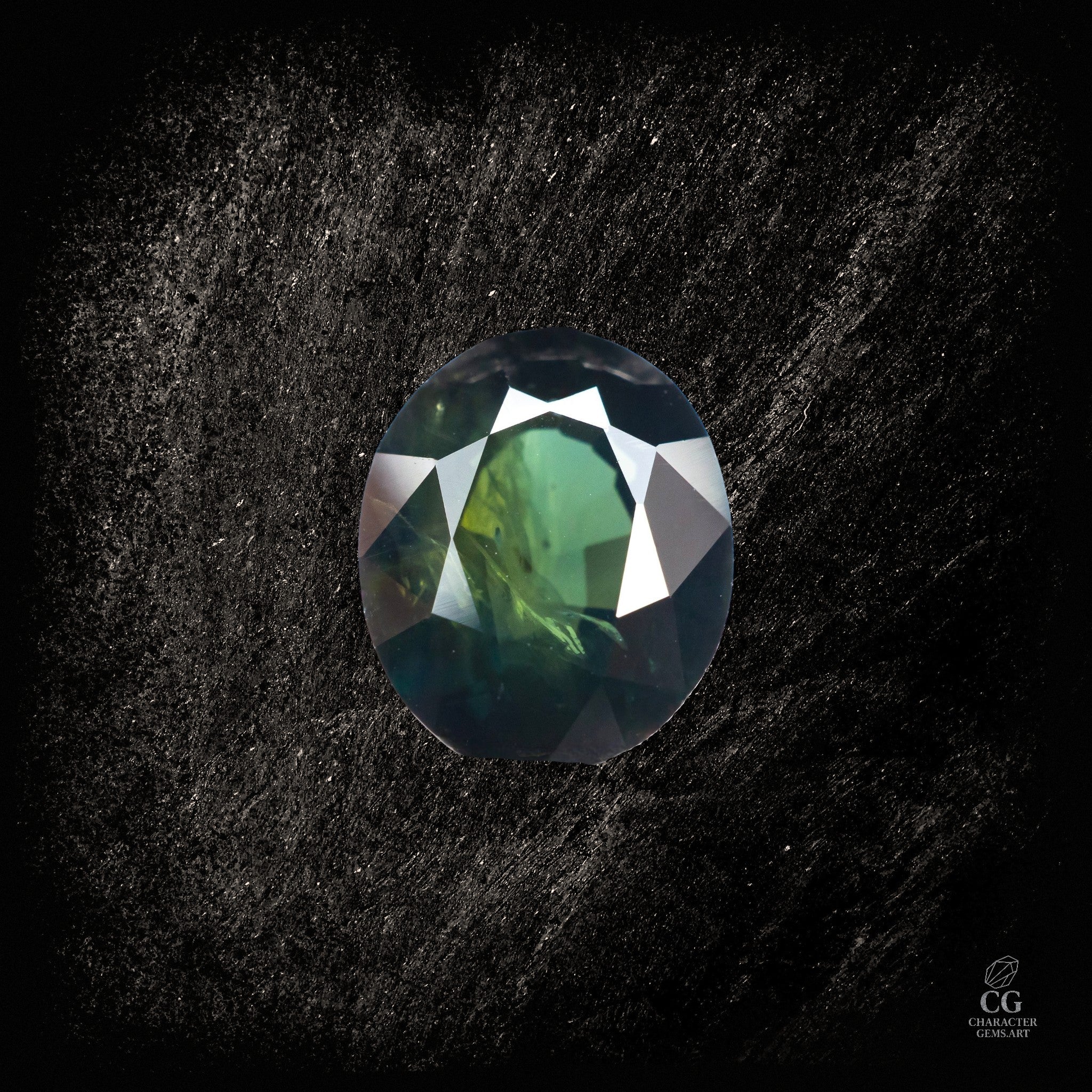 Blauer Saphir von Character Gemstones, 2,19 Karat, mit grünlichem Obsidian-Hintergrund, detailreiche Edelsteinaufnahme.