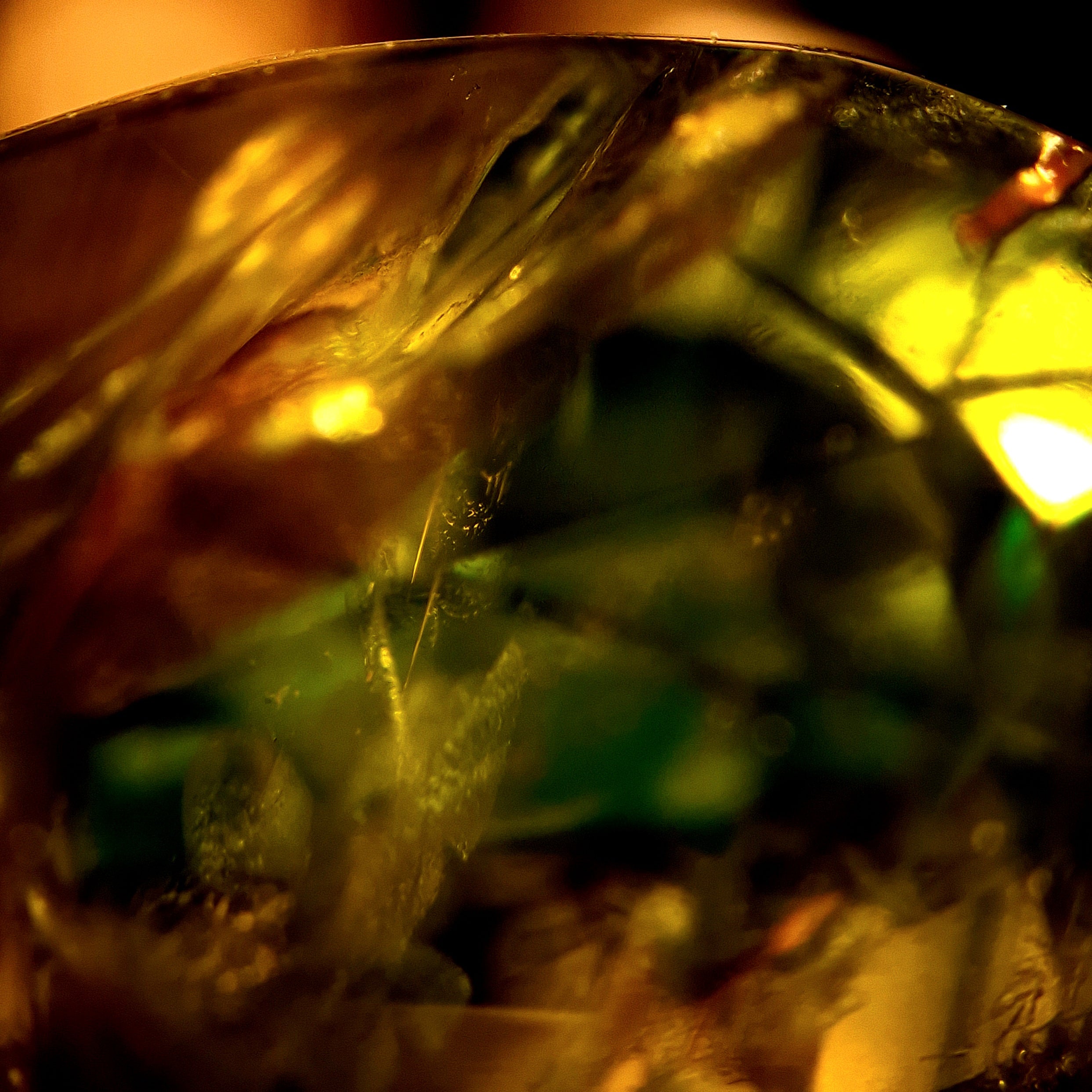 Makrofotografie eines Edelsteins mit gold-grünen Farbstrukturen und inneren Formationen aus der Serie Micro Landscapes