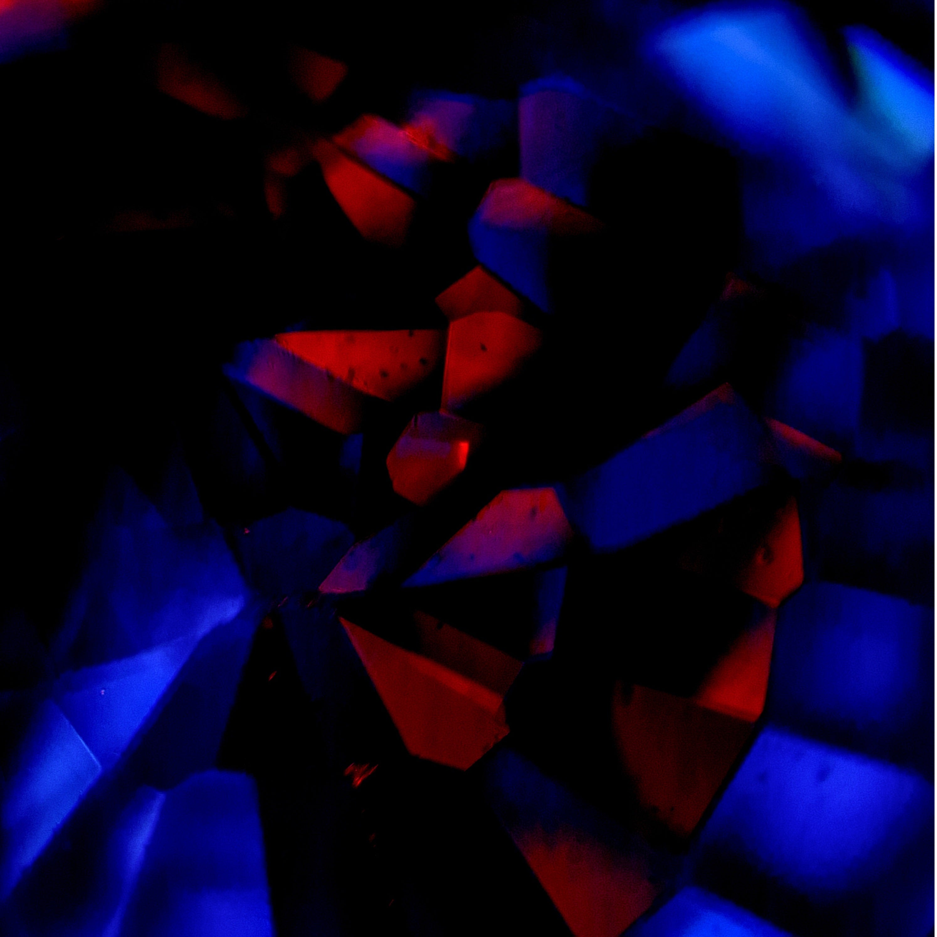 Makrofotografie eines Spinells aus Tansania mit blau-rotem Farbspektrum und facettierten Lichtreflexen